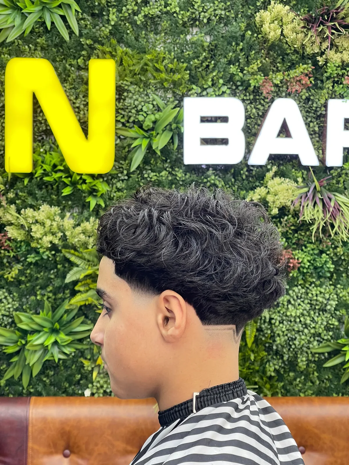 Curly haircut with a clean fade and sharp neckline